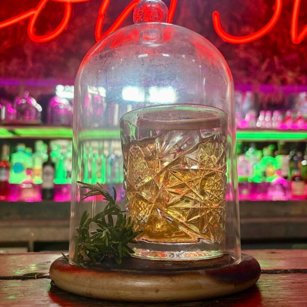 Old Fashioned cocktail under a glass case in a cocktail bar